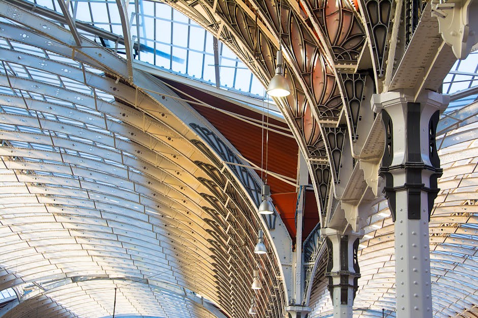 Inside the recently renovated Paddington Station, the image shows a spacious platform area with a high, curved glass and metal roof allowing natural light to illuminate the space. Alongside the platfo